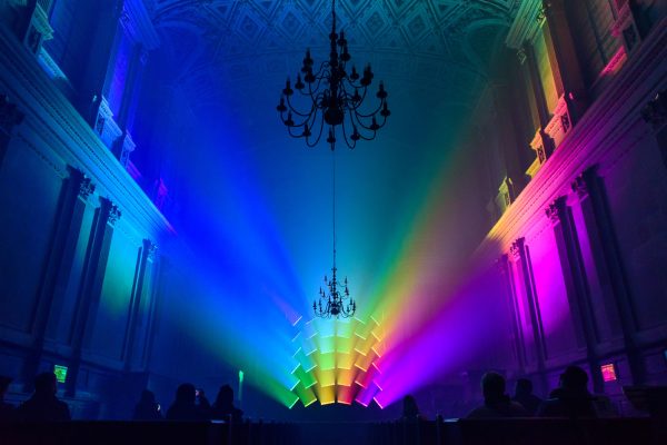 a captured moment during a live light and music installation at St Marys in the Strand, London which was led by Bec Smith a GLOW artist residency recipient. What is visible is the altar, a panel of lights which are creating a dynamic rainbow of colours.